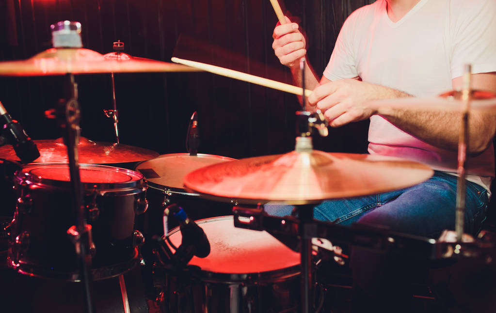 музыка, люди, музыкальные инструменты и развлекательная концепция - мужчина музыкант или барабанщик, играющий на ударных в студии на фоне праздничных огней
. - Фото, изображение