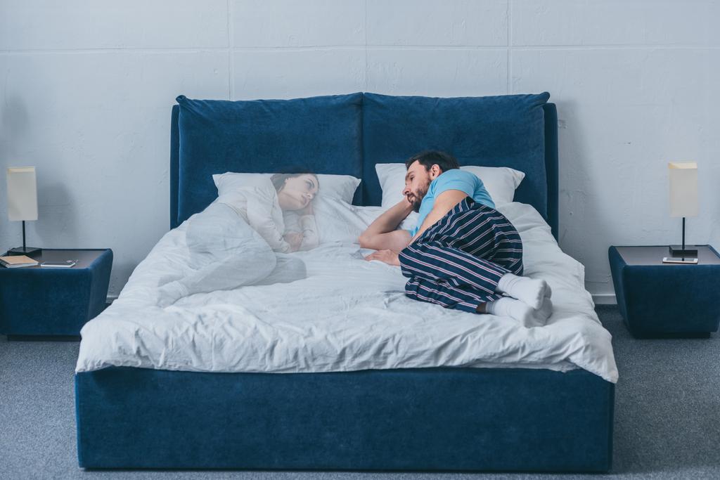depressed man lying in bed and looking at wife ghost - Photo, Image