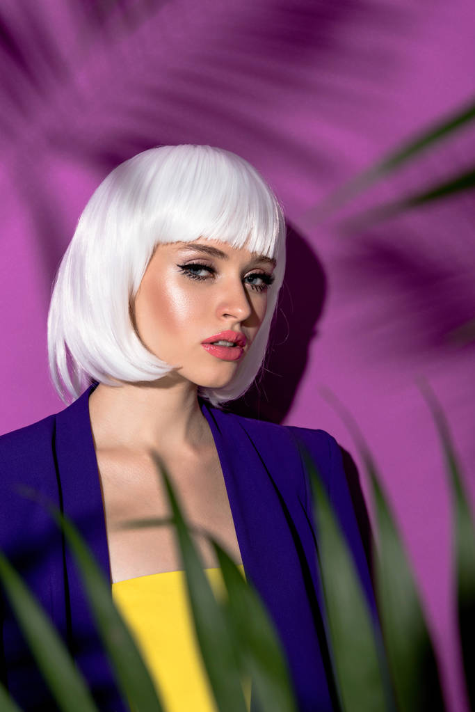 Pretty young woman in white wig looking at camera at purple background - Photo, Image