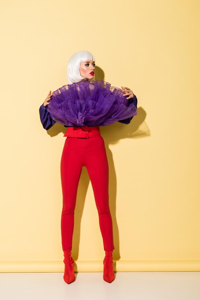 Fashionable girl in red pants looking away on yellow background - Photo, Image