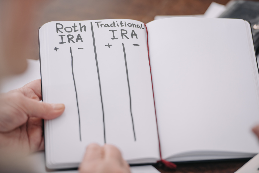 partial view of senior woman holding notebook with roth ira and traditional ira words - Photo, Image