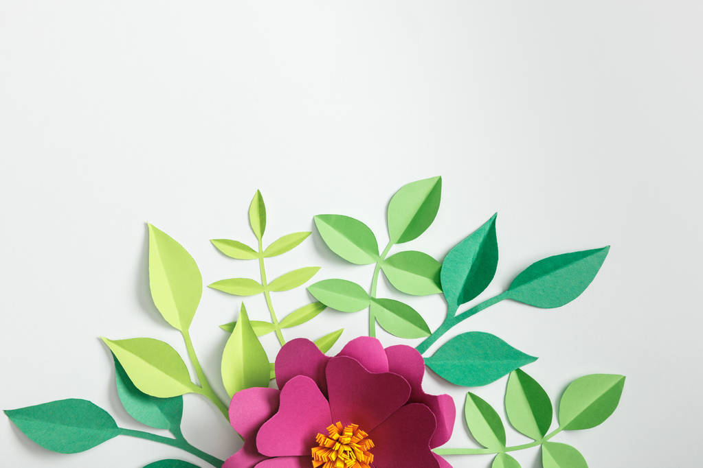 вид сверху на розовый бумажный цветок и зеленые растения на сером фоне
 - Фото, изображение