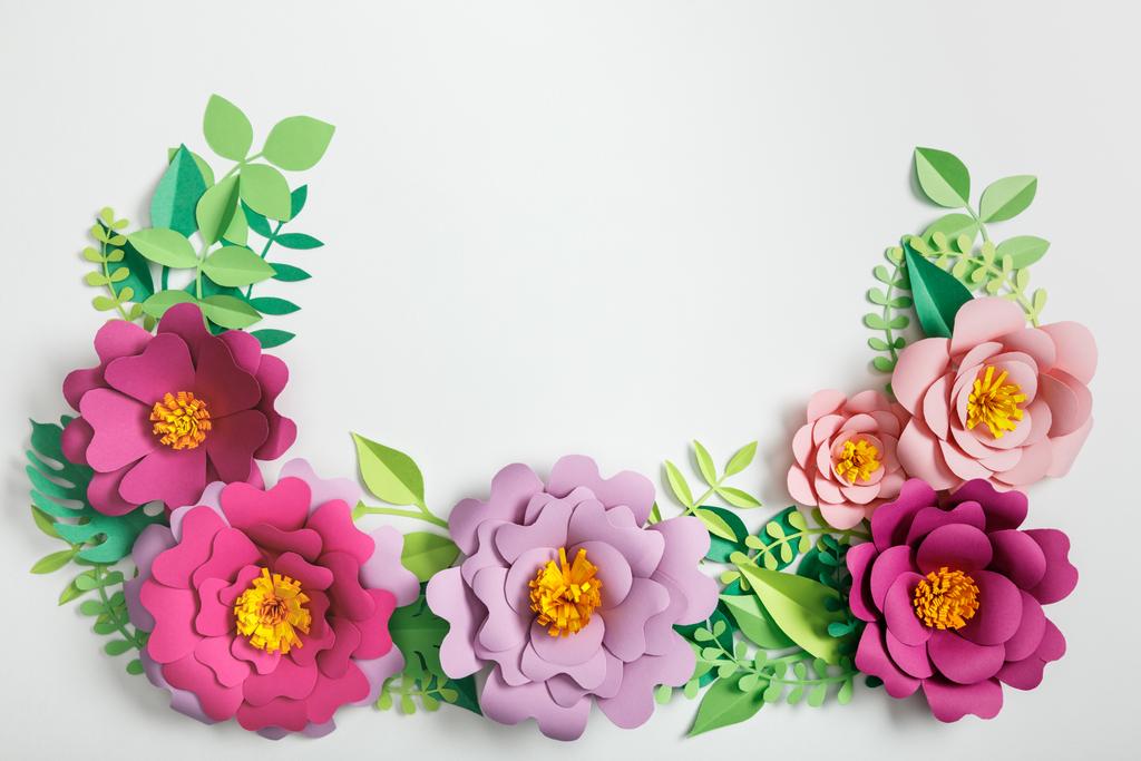 top view of pink and lilac paper flowers and green plants with leaves on grey background - Photo, Image