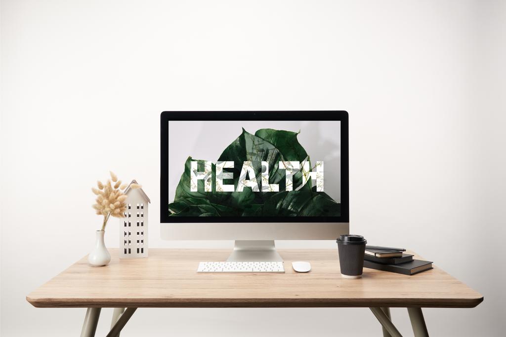 υπολογιστή με πράσινα φύλλα και υγεία γράμματα στην οθόνη πάνω στο ξύλινο γραφείο - Φωτογραφία, εικόνα