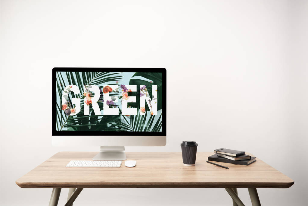 computer with green leaves and green lettering on monitor on wooden desk - Photo, Image