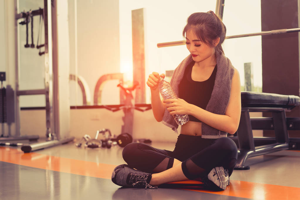 Γυναίκα άσκησης προπόνηση στο γυμναστήριο fitness σπάσιμο χαλαρώσετε ανοικτό νερό ανάκαμψη μετά κατάρτισης αθλητισμού με αλτήρα και πρωτεΐνη ανακινείται μπουκάλι bodybuilding υγιεινού τρόπου ζωής. - Φωτογραφία, εικόνα