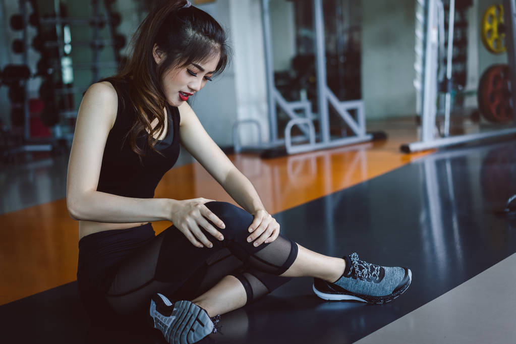 Kobieta robi sport ćwiczenia kolana wypadek w siłowni fitness  - Zdjęcie, obraz
