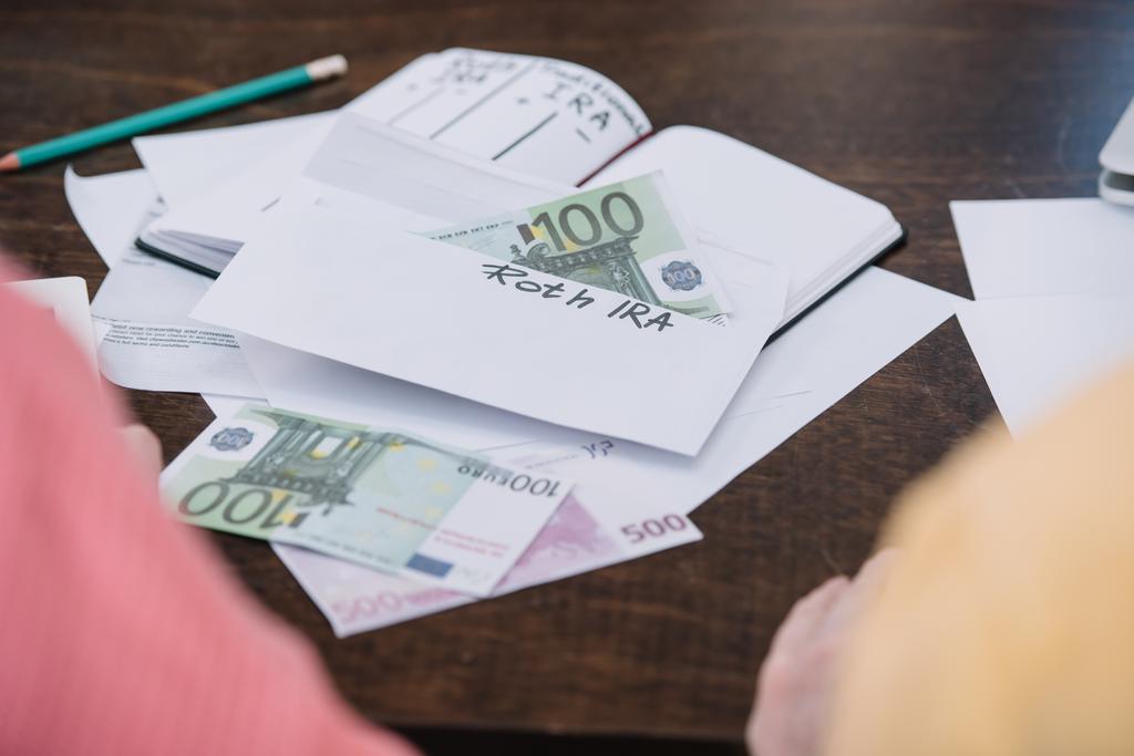 selective focus of envelope with 'roth ira' lettering and money on table - Photo, Image