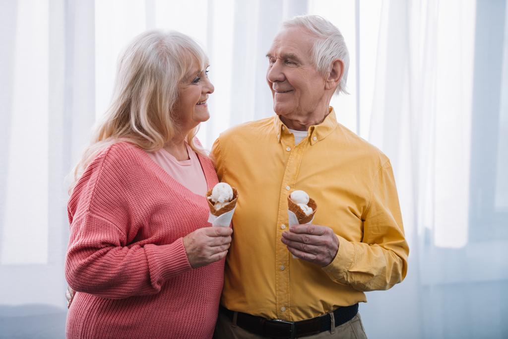 ανώτερος ζευγάρι βλέπουν ο ένας τον άλλον και κρατώντας στο σπίτι χωνάκια παγωτού  - Φωτογραφία, εικόνα
