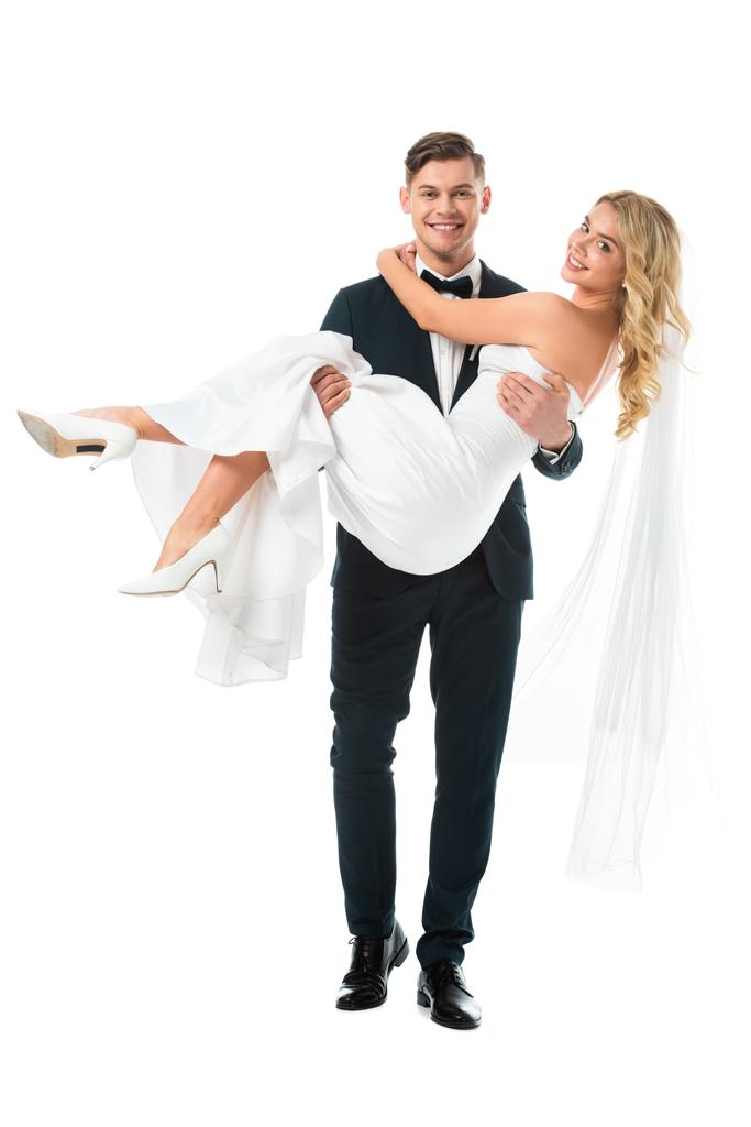 Happy pohledný ženich drží krásná nevěsta na rukou izolované na bílém - Fotografie, Obrázek