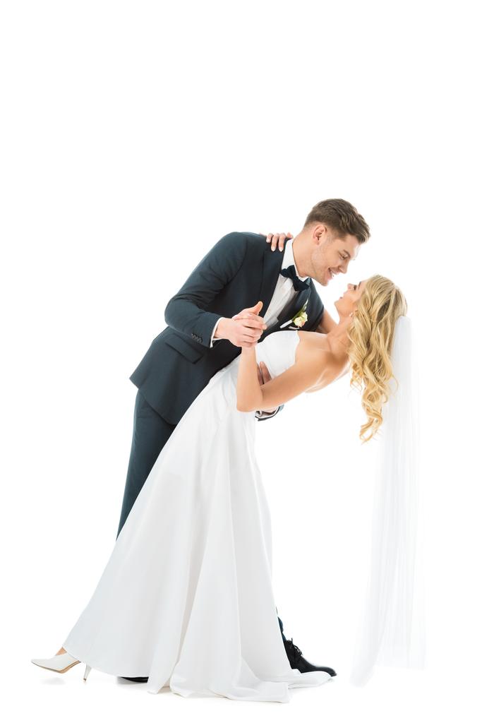 όμορφος groom σε κομψό κοστούμι, χορός με όμορφη νύφη στο γάμο φόρεμα που απομονώνονται σε λευκό - Φωτογραφία, εικόνα