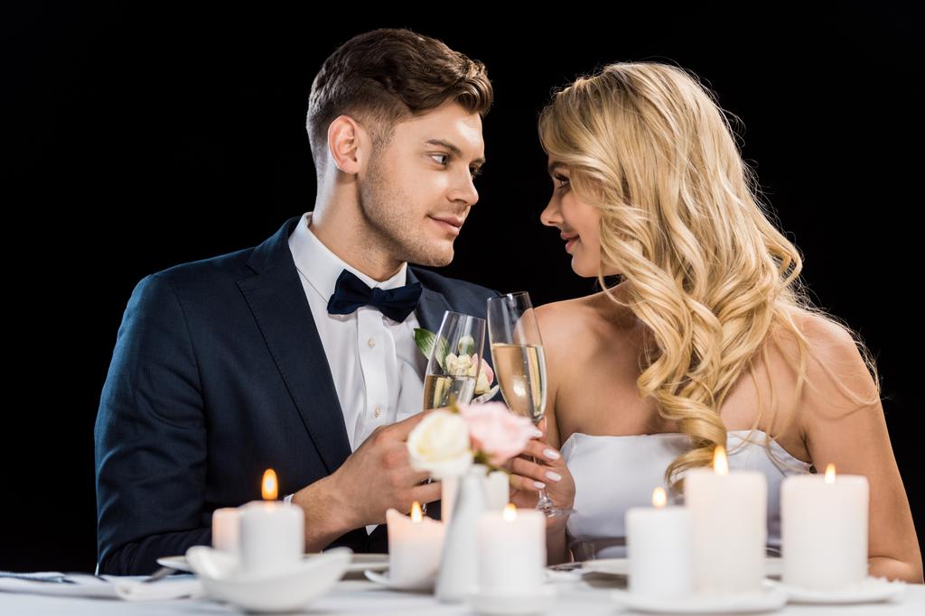 усміхнений наречений і наречена смердить келихи шампанського і дивиться один на одного ізольовані на чорному
 - Фото, зображення