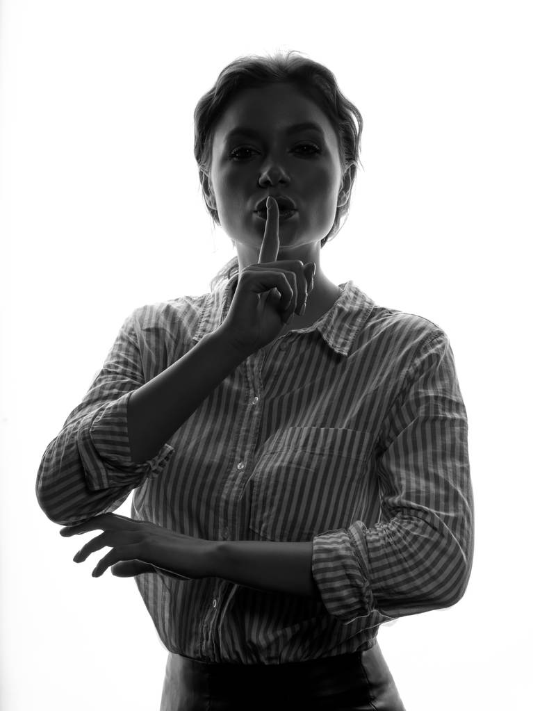 Porträt einer jungen lockigen Frau im gestreiften Hemd, die Schweigegegeste auf weißem Hintergrund aussät - Foto, Bild