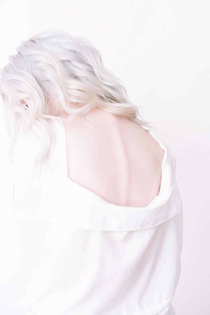 Joven novia linda con hermoso peinado en un vestido blanco sobre un fondo gris en el estudio
 - Foto, Imagen