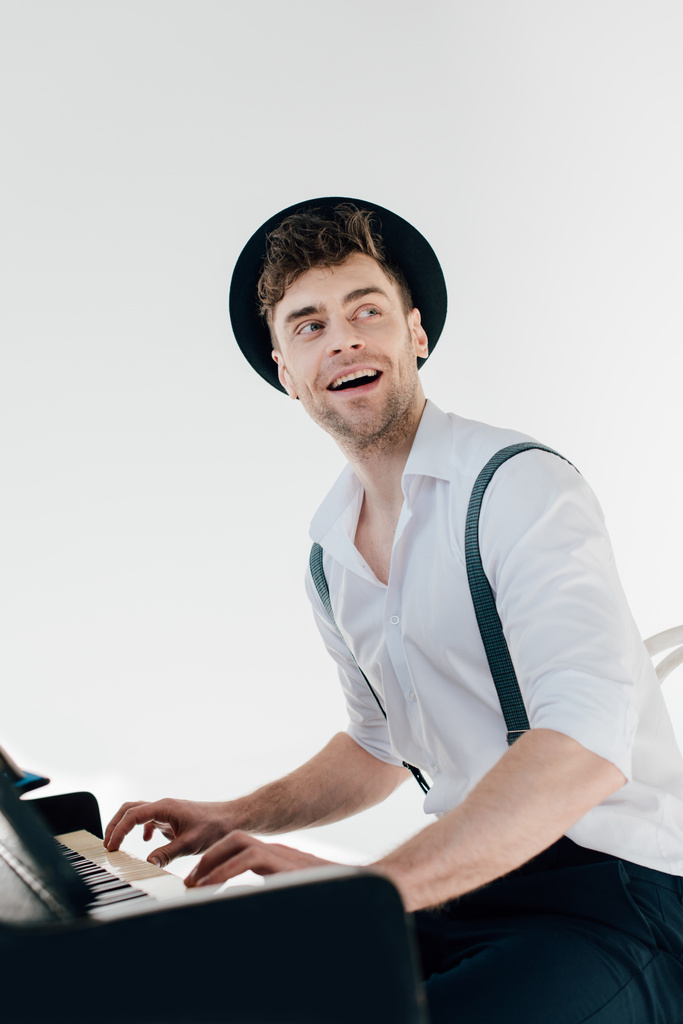 陽気な白いシャツと黒い帽子のピアノを弾くピアニスト  - 写真・画像