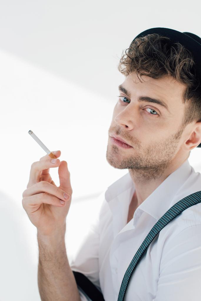 bel homme tenant cigarette et regardant la caméra
  - Photo, image