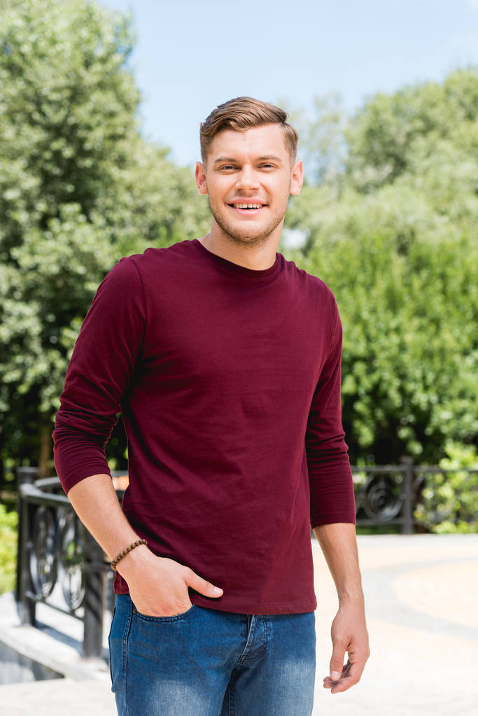 happy young man smiling while standing with hand in pocket - Photo, Image
