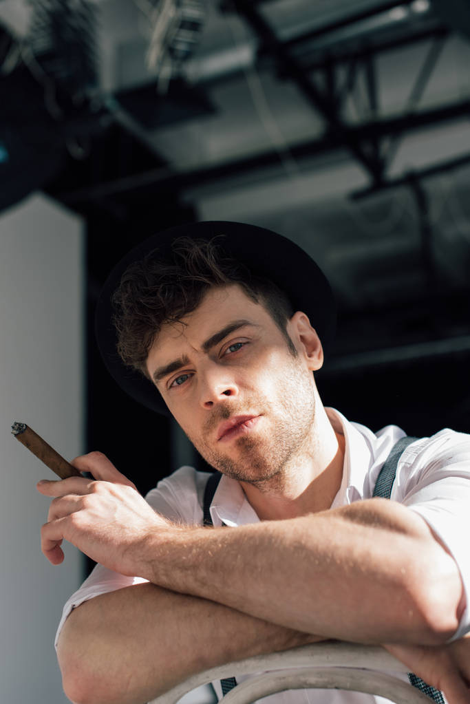 guapo pensativo hombre fumando cigarro y mirando a la cámara
 - Foto, Imagen