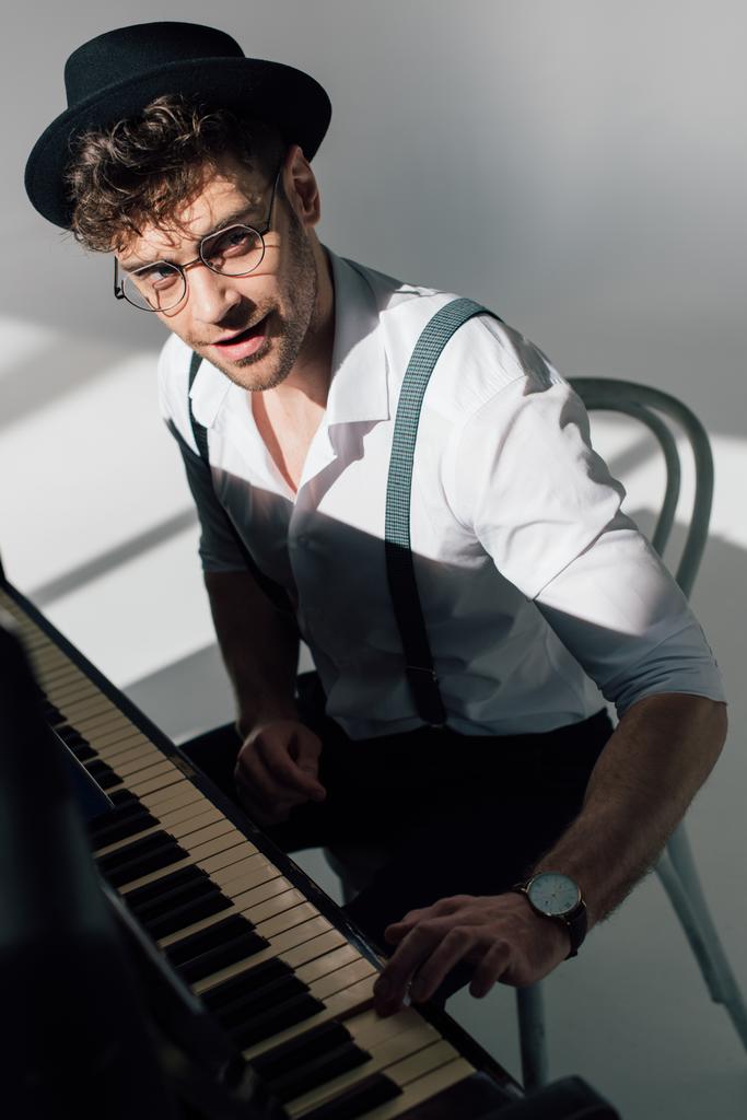 s úsměvem hudebník v brýlích hraje klavírní a vypadající na kameru  - Fotografie, Obrázek
