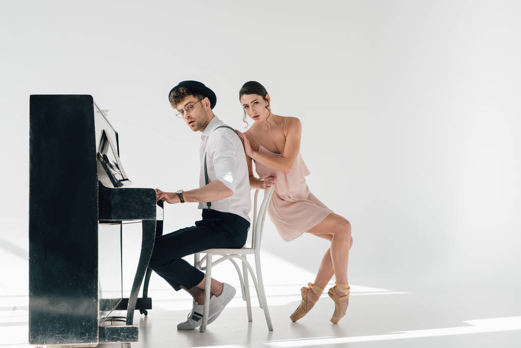 houkutteleva ballerina koskettaa komea muusikko soittaa pianoa
  - Valokuva, kuva