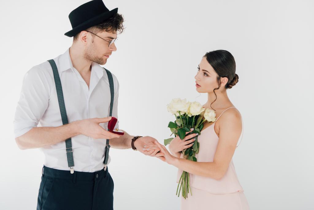 hombre guapo en ropa de moda haciendo propuesta de matrimonio a hermosa chica sosteniendo ramo de rosas
  - Foto, imagen