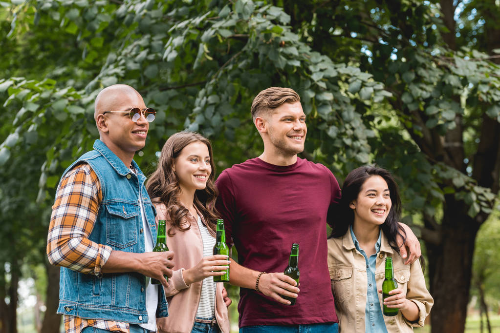 grupo multiétnico feliz de amigos segurando garrafas com cerveja no parque
 - Foto, Imagem