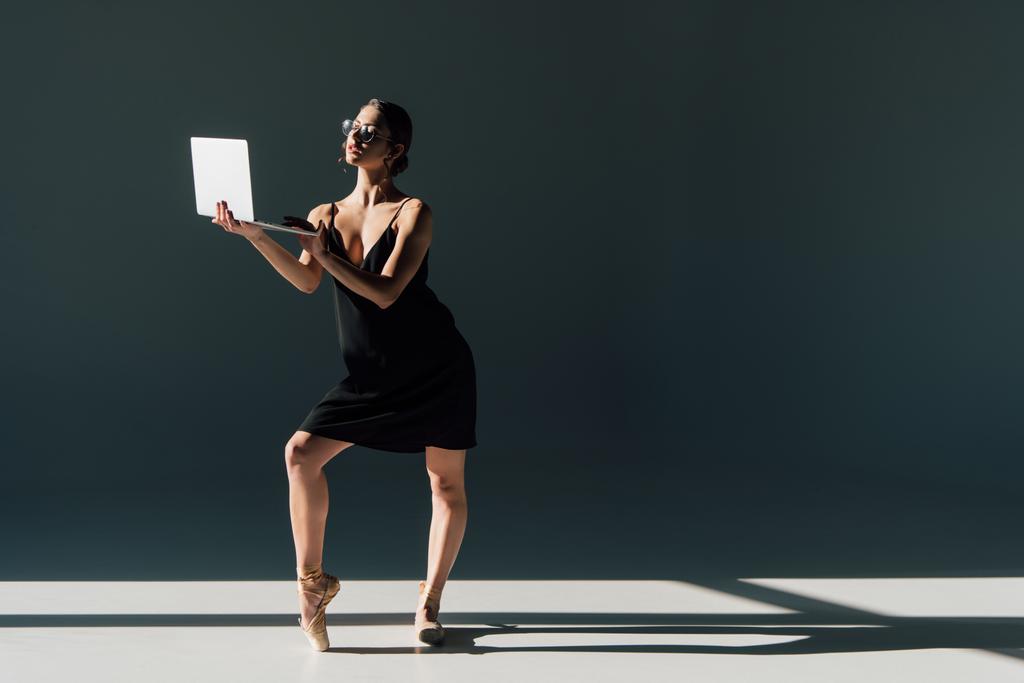 bela bailarina em vestido preto e óculos posando com laptop
  - Foto, Imagem
