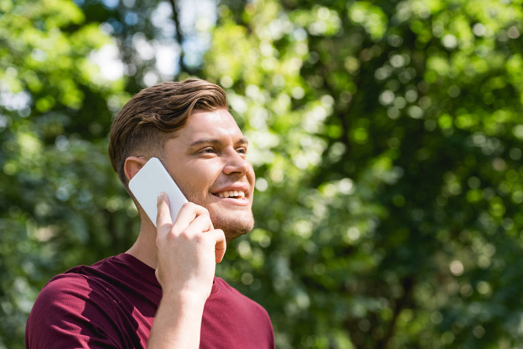 щасливий молодий чоловік розмовляє на смартфоні в парку
 - Фото, зображення
