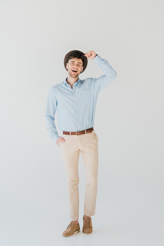 cheerful man in blue shirt and beige jeans looking at camera isolated on grey - Photo, Image