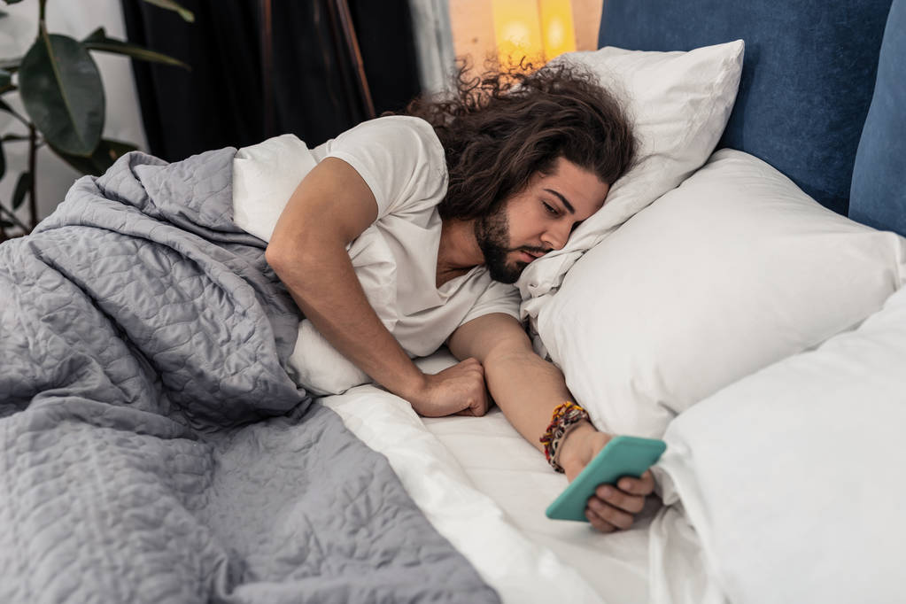 Bel homme brune couché avec son smartphone
 - Photo, image
