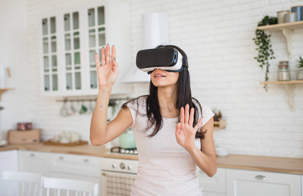 Jovem mulher em óculos VR na cozinha em casa
 - Foto, Imagem
