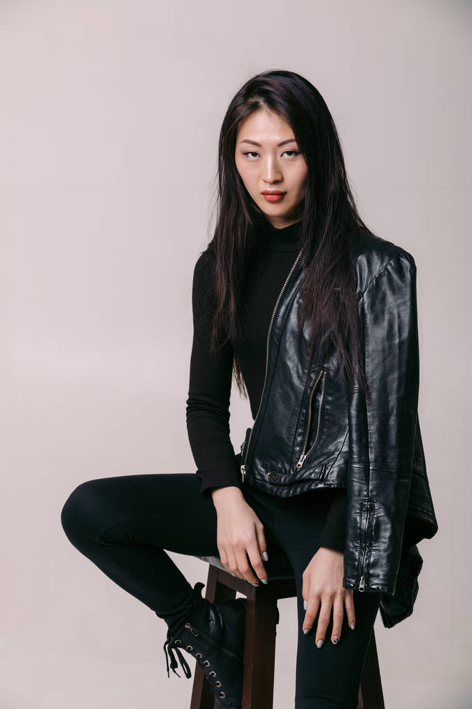 Aziatische model in zwarte jas poseren in studio - Foto, afbeelding