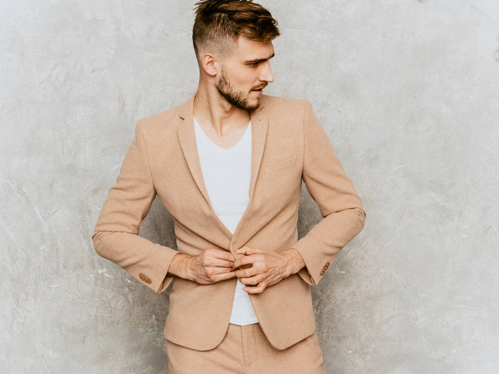 Portret van knappe ernstige moderne hipster lumbersexual zakenman model dragen casual beige kleur. Stijlvolle man mode poseren tegen grijze muur - Foto, afbeelding