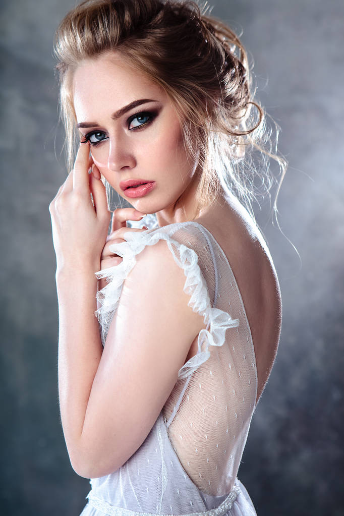 Nevěsta blondýnka v moderních barevných svatebních šatech s elegantním účesu a make-up. Módní portrét v pozadí s texturou - Fotografie, Obrázek