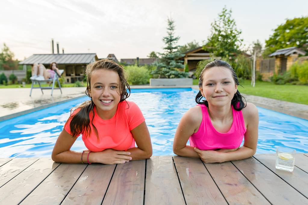Dwie młode Nastolatki dziewczyny zabawy w basenie, uśmiechając się, patrząc w kamerę - Zdjęcie, obraz
