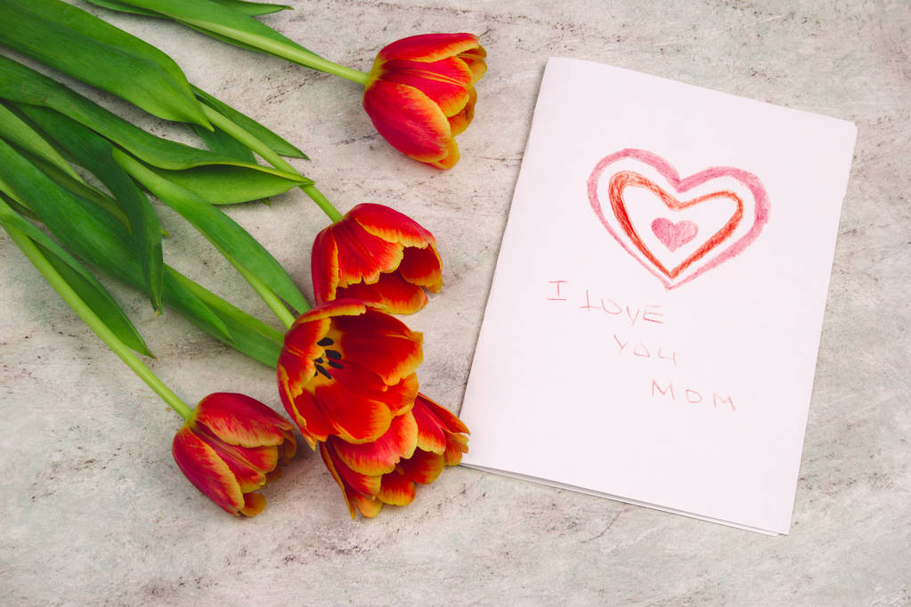 красивые тюльпаны и открытка ручной работы с детским рисунком на День матери на мраморном фоне, вид сверху
 - Фото, изображение
