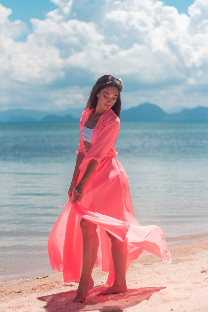 Πορτρέτο της νεαρής γυναίκας που φοράει ένα ροζ σαρόνγκ και μπικίνι στην τροπική παραλία - Φωτογραφία, εικόνα