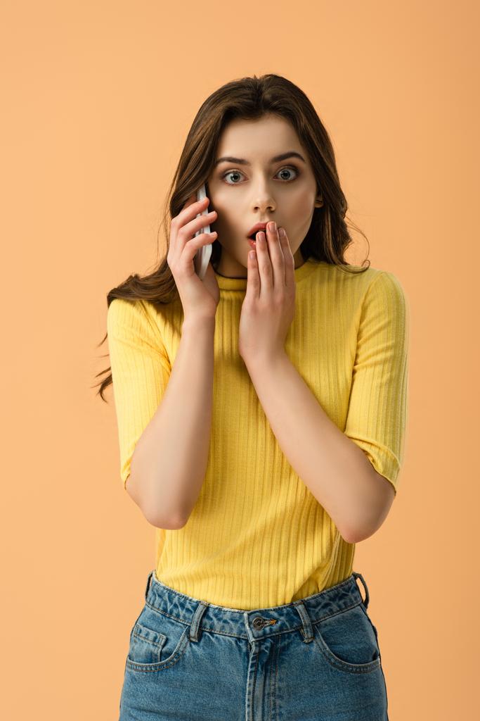 järkyttynyt nuori nainen puhuu älypuhelimella ja peittää suun eristetty oranssi
  - Valokuva, kuva