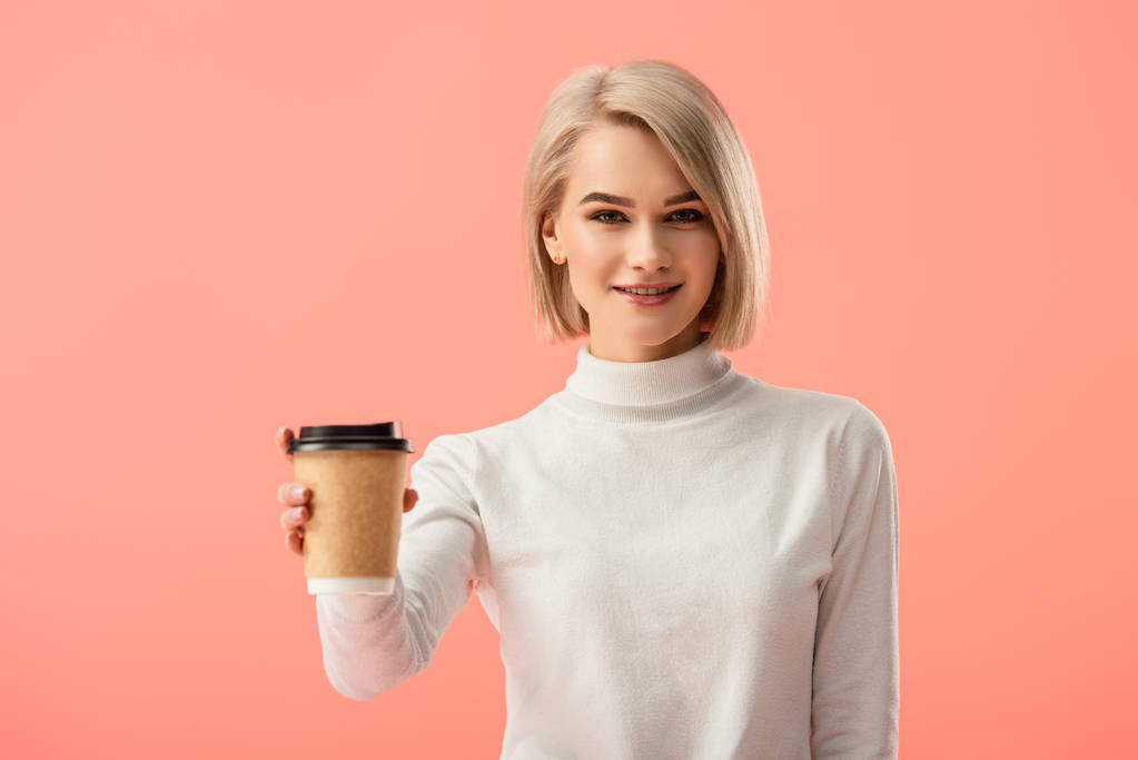 selective focus of cheerful blonde girl holding paper cup with drink isolated on pink  - Photo, Image