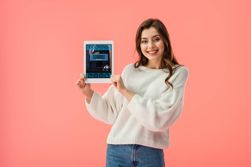 heureuse jeune femme tenant tablette numérique avec application de réservation à l'écran isolé sur rose
  - Photo, image
