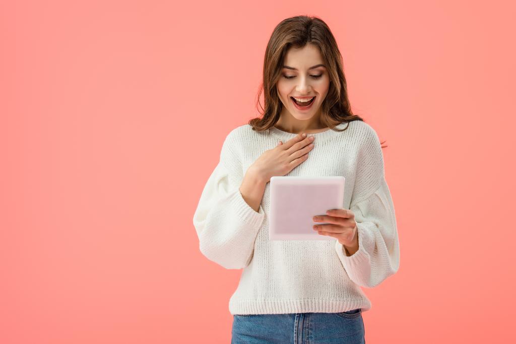 yllättynyt ja houkutteleva nuori nainen tilalla digitaalinen tabletti eristetty vaaleanpunainen
   - Valokuva, kuva