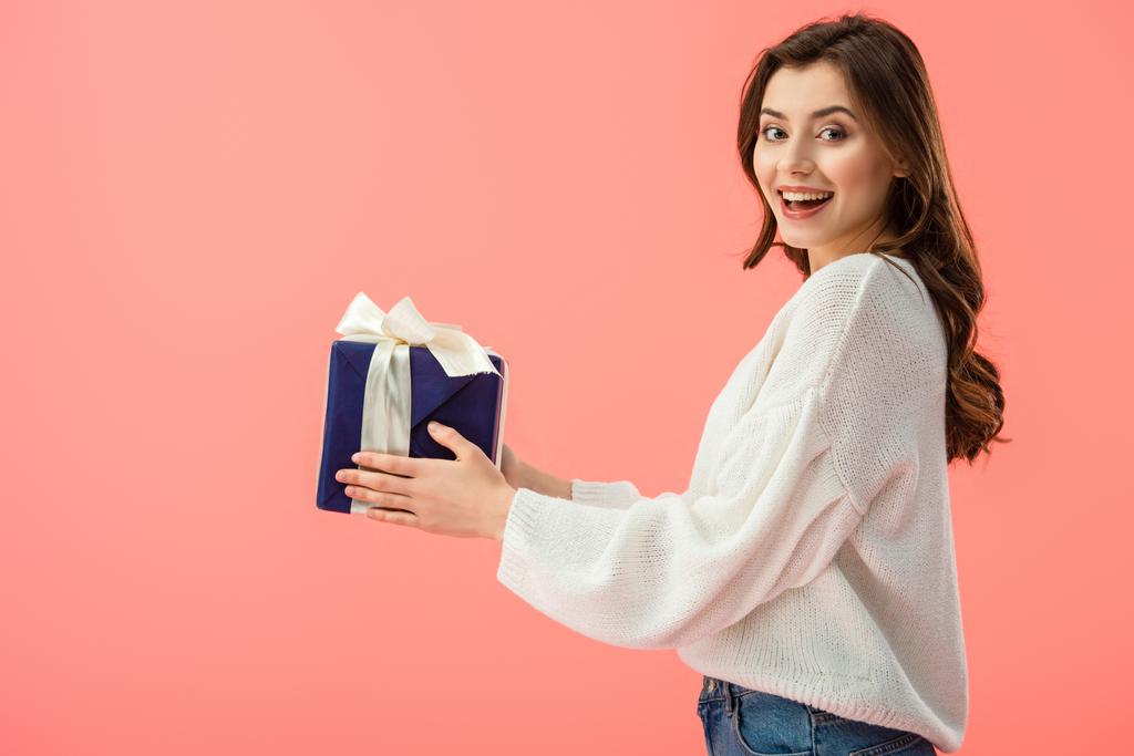 usměvavá a atraktivní žena v bílém svetru drží izolované na růžová dárková krabička  - Fotografie, Obrázek
