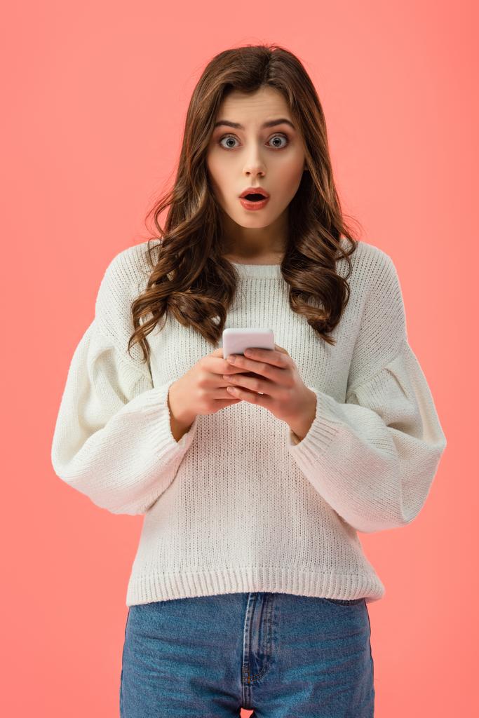 sorprendió a mujer joven en suéter blanco sosteniendo teléfono inteligente aislado en rosa
 - Foto, imagen