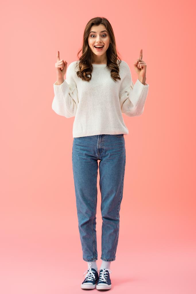 visão de comprimento total de mulher sorridente e bonita em suéter branco apontando com os dedos
  - Foto, Imagem