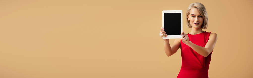 plano panorámico de mujer en vestido rojo sosteniendo tableta digital con pantalla en blanco aislado en beige
 - Foto, imagen