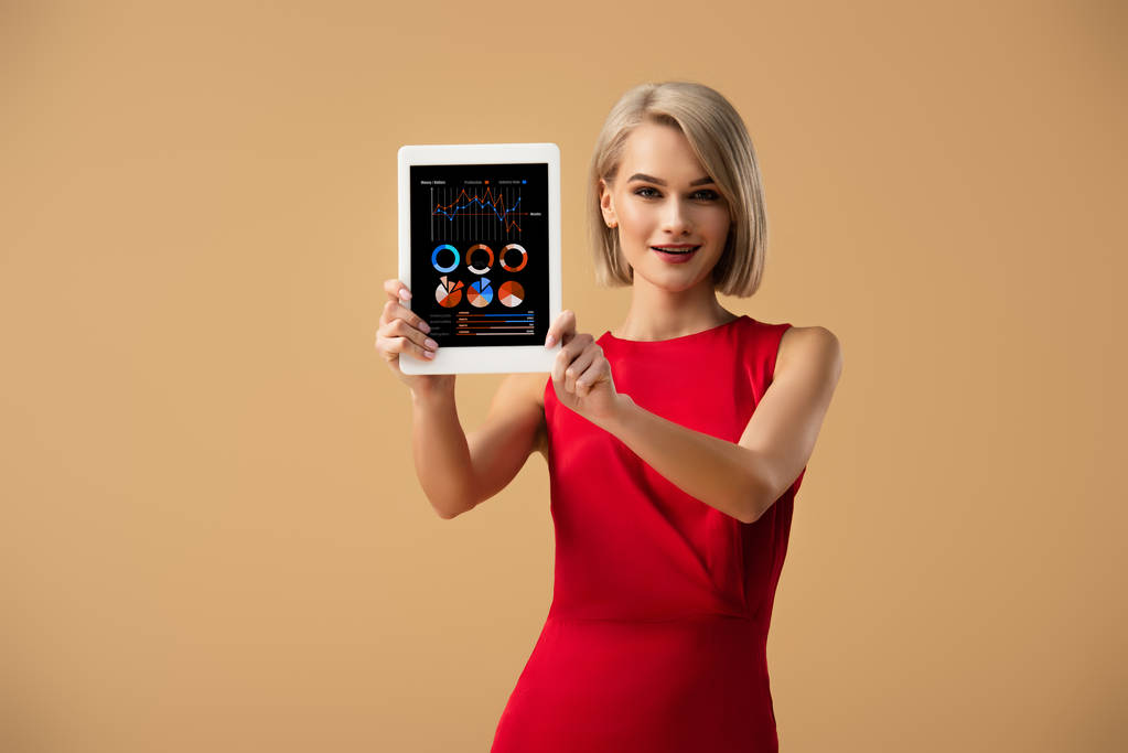 Çizelgeler ve grafikler ile dijital tablet üzerinde bej izole ekran üzerinde tutan Kırmızı elbiseli güzel kadın - Fotoğraf, Görsel