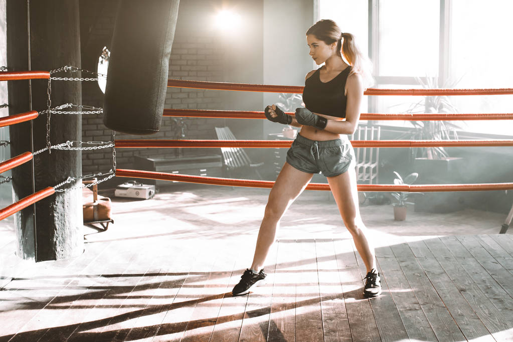 Uma pugilista a bater num saco enorme num estúdio de boxe. Mulher boxer formação duro
. - Foto, Imagem