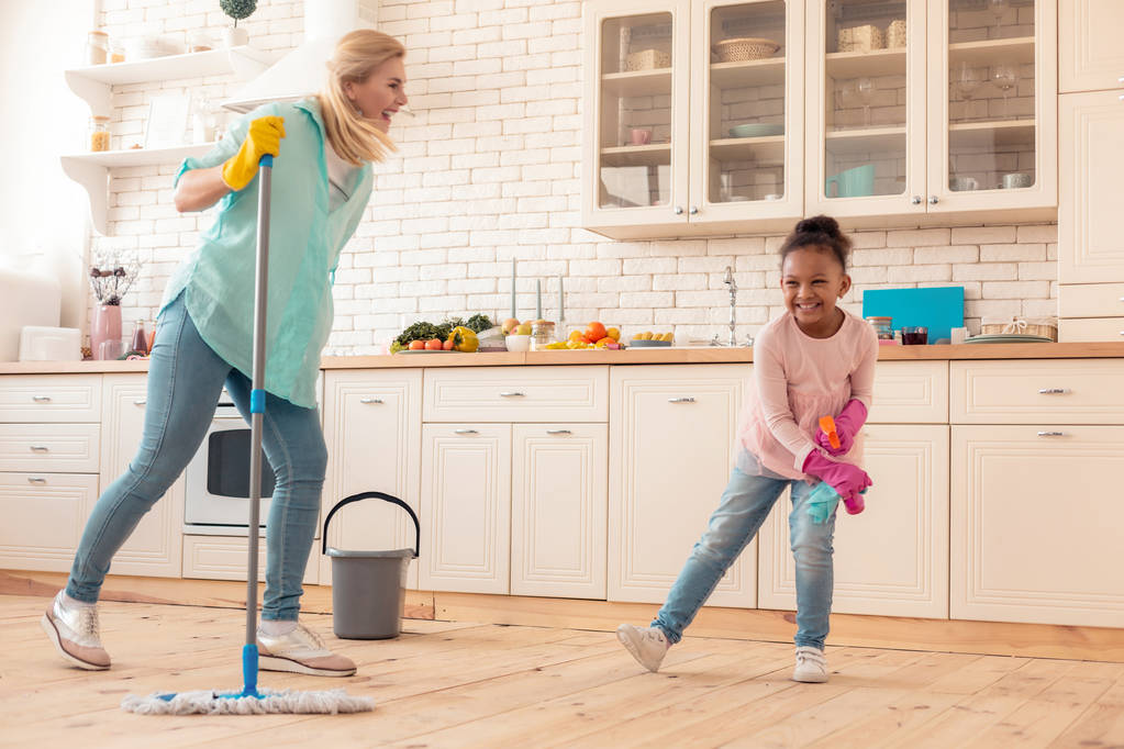 Allegra figlia adottiva ridere mentre pulisce la cucina con la mamma
 - Foto, immagini