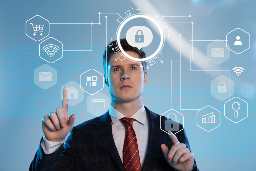 bell'uomo d'affari in giacca e cravatta che punta con le dita le icone della sicurezza informatica davanti su sfondo blu
 - Foto, immagini