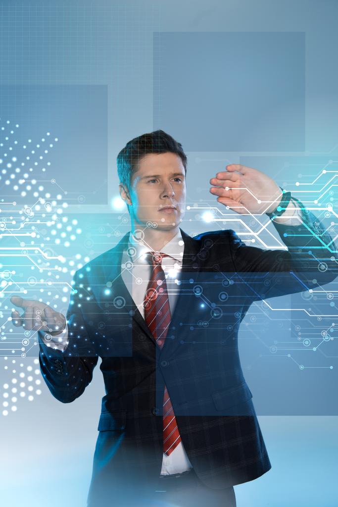 handsome businessman in suit pointing at network illustration in front on blue background - Photo, Image